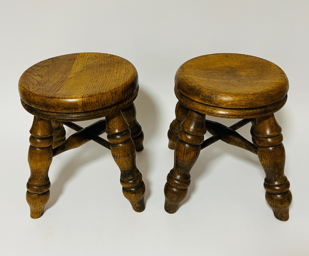 A pair of small antique oak stools with circular dished tops, turned baluster legs, and cross stretchers. View II