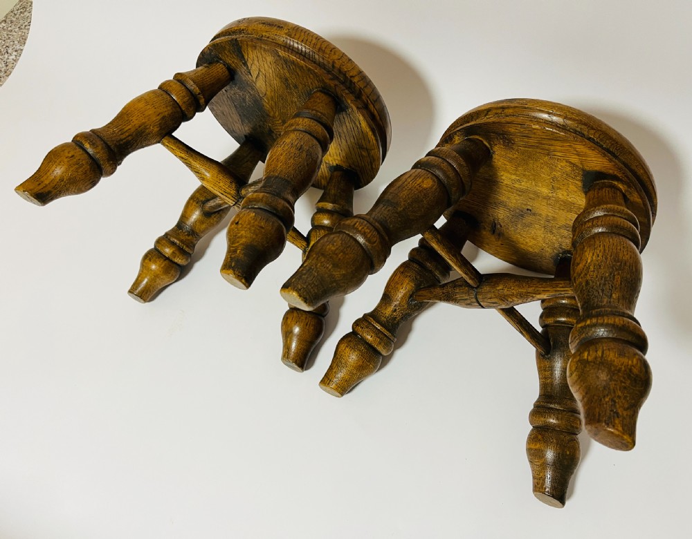 A pair of small antique oak stools with circular dished tops, turned baluster legs, and cross stretchers. View V