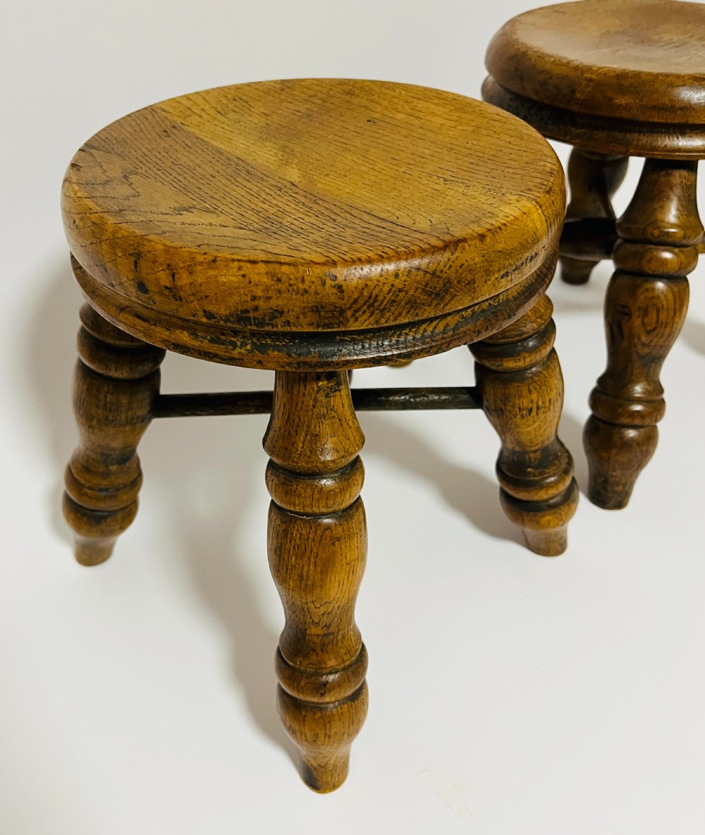 A pair of small antique oak stools with circular dished tops, turned baluster legs, and cross stretchers. View VII
