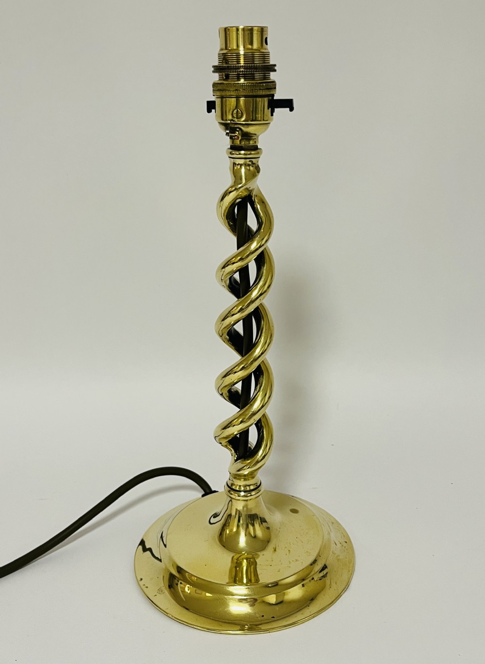 A polished brass table lamp featuring an open barley twist column set upon a round stepped base.
