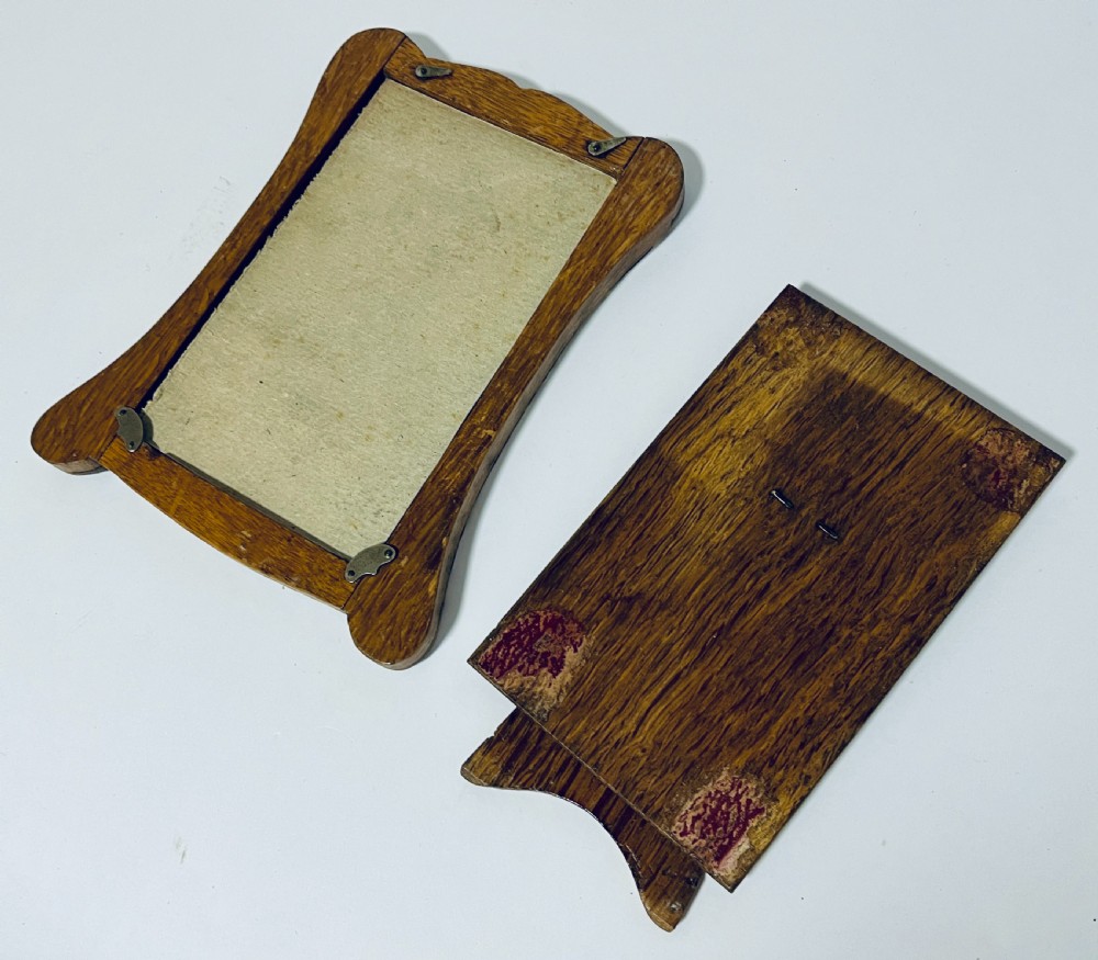 An antique silver picture frame featuring a curved scalloped rim, visible hallmarks along the lower border, and a dark textured interior display panel. View IX
