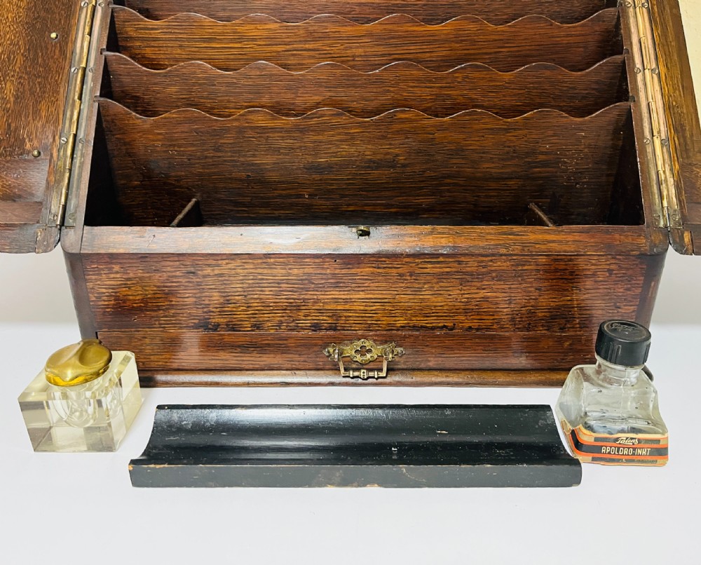 An open Victorian dark oak stationery cabinet featuring fitted letter slots, an integrated perpetual calendar, twin inkwells, and hinged side doors. View V