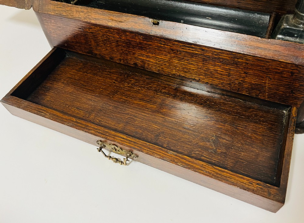 An open Victorian dark oak stationery cabinet featuring fitted letter slots, an integrated perpetual calendar, twin inkwells, and hinged side doors. View VI