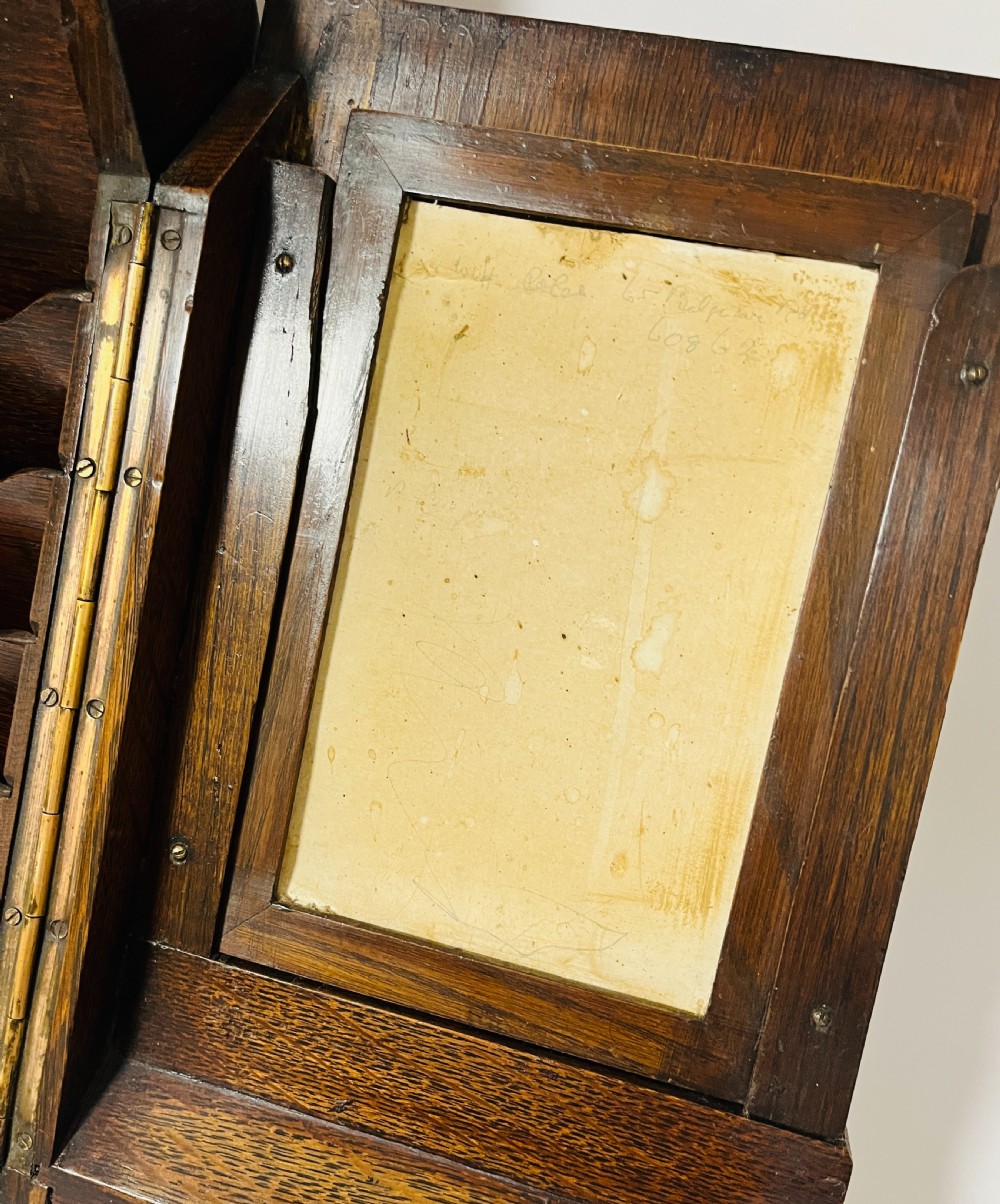 An open Victorian dark oak stationery cabinet featuring fitted letter slots, an integrated perpetual calendar, twin inkwells, and hinged side doors. View VIII