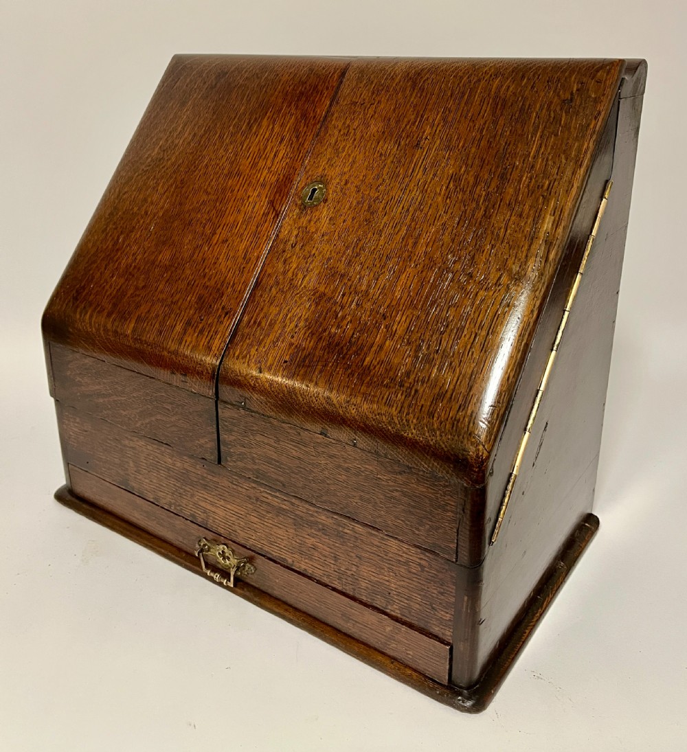 An open Victorian dark oak stationery cabinet featuring fitted letter slots, an integrated perpetual calendar, twin inkwells, and hinged side doors. View IX