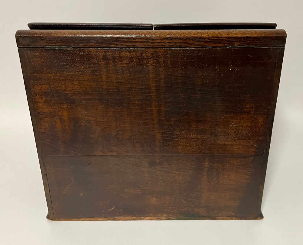 An open Victorian dark oak stationery cabinet featuring fitted letter slots, an integrated perpetual calendar, twin inkwells, and hinged side doors. View X