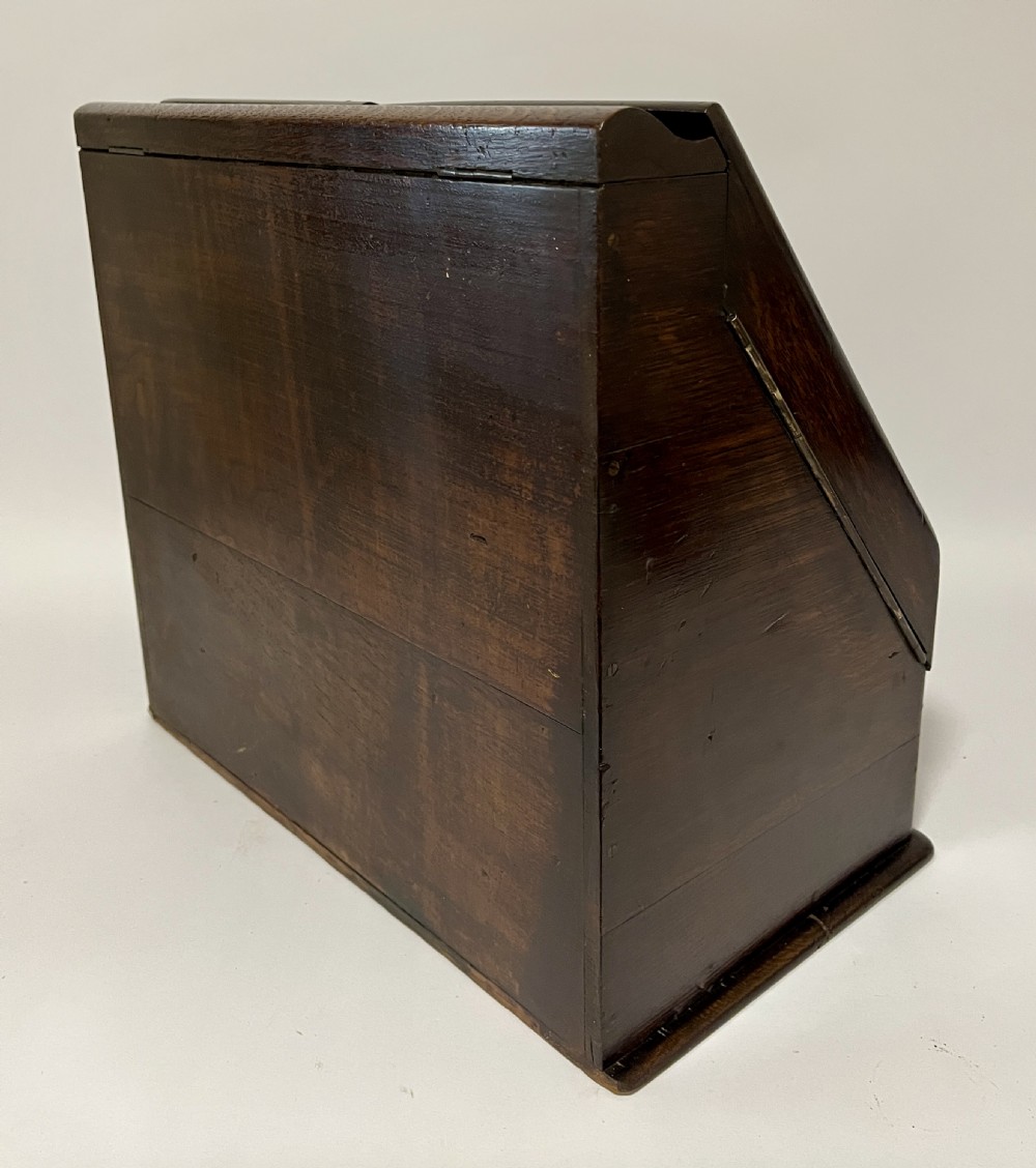 An open Victorian dark oak stationery cabinet featuring fitted letter slots, an integrated perpetual calendar, twin inkwells, and hinged side doors. View XI