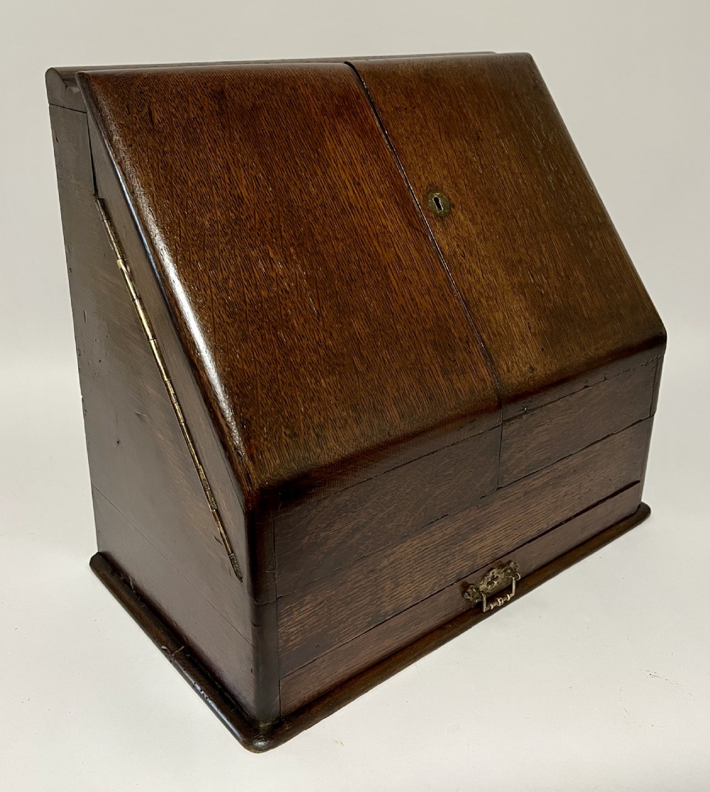 An open Victorian dark oak stationery cabinet featuring fitted letter slots, an integrated perpetual calendar, twin inkwells, and hinged side doors. View XIII