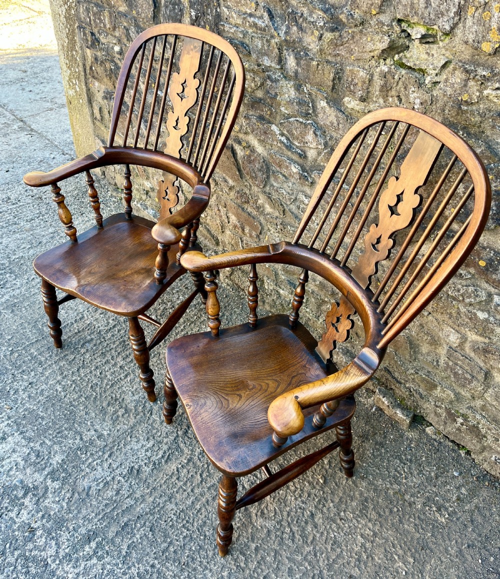 A pair of antique wooden Windsor armchairs featuring curved hoop backs, pierced central splats, broad armrests, and turned legs. View II