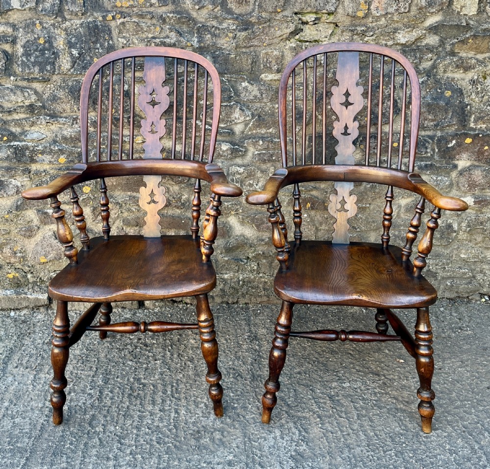 A pair of antique wooden Windsor armchairs featuring curved hoop backs, pierced central splats, broad armrests, and turned legs. View III