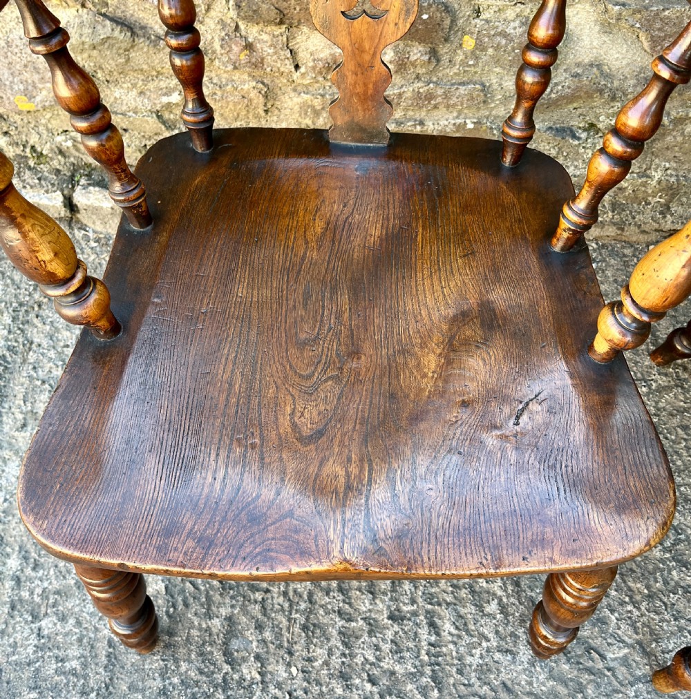 A pair of antique wooden Windsor armchairs featuring curved hoop backs, pierced central splats, broad armrests, and turned legs. View V
