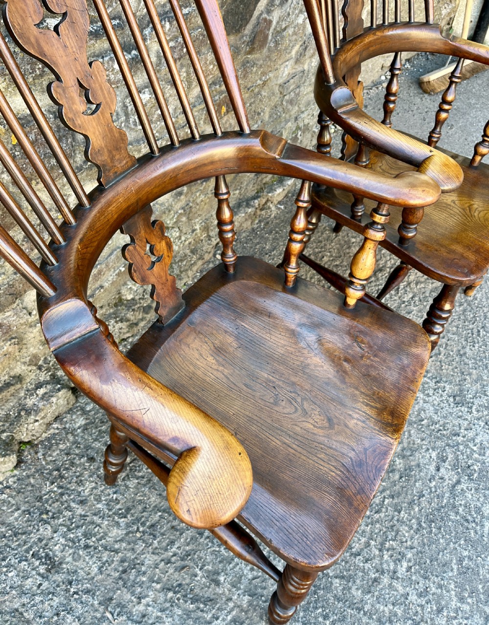 A pair of antique wooden Windsor armchairs featuring curved hoop backs, pierced central splats, broad armrests, and turned legs. View VI