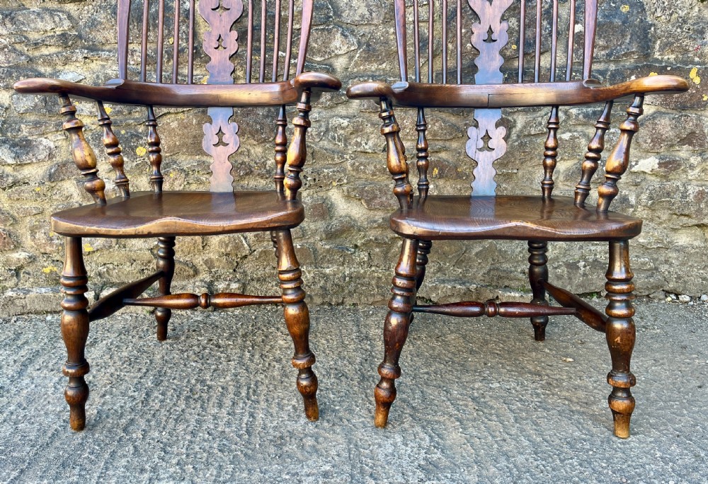 A pair of antique wooden Windsor armchairs featuring curved hoop backs, pierced central splats, broad armrests, and turned legs. View IX
