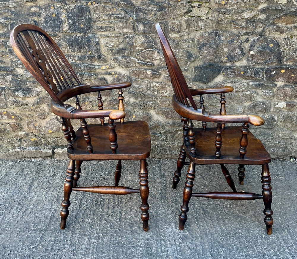 A pair of antique wooden Windsor armchairs featuring curved hoop backs, pierced central splats, broad armrests, and turned legs. View XII
