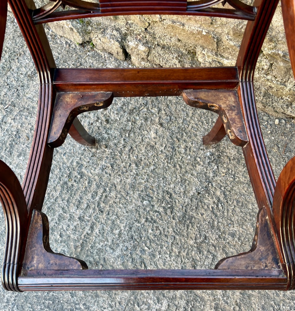 A Regency mahogany armchair featuring reeded scroll arms, a carved back splat, swept legs, and a deep red leather seat. View VIII