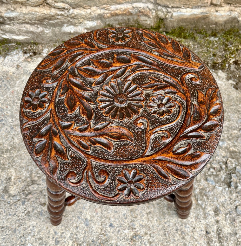 A small dark oak tripod table featuring bobbin-turned legs, a central turned stretcher, and a circular top hand-carved with floral patterns. View II