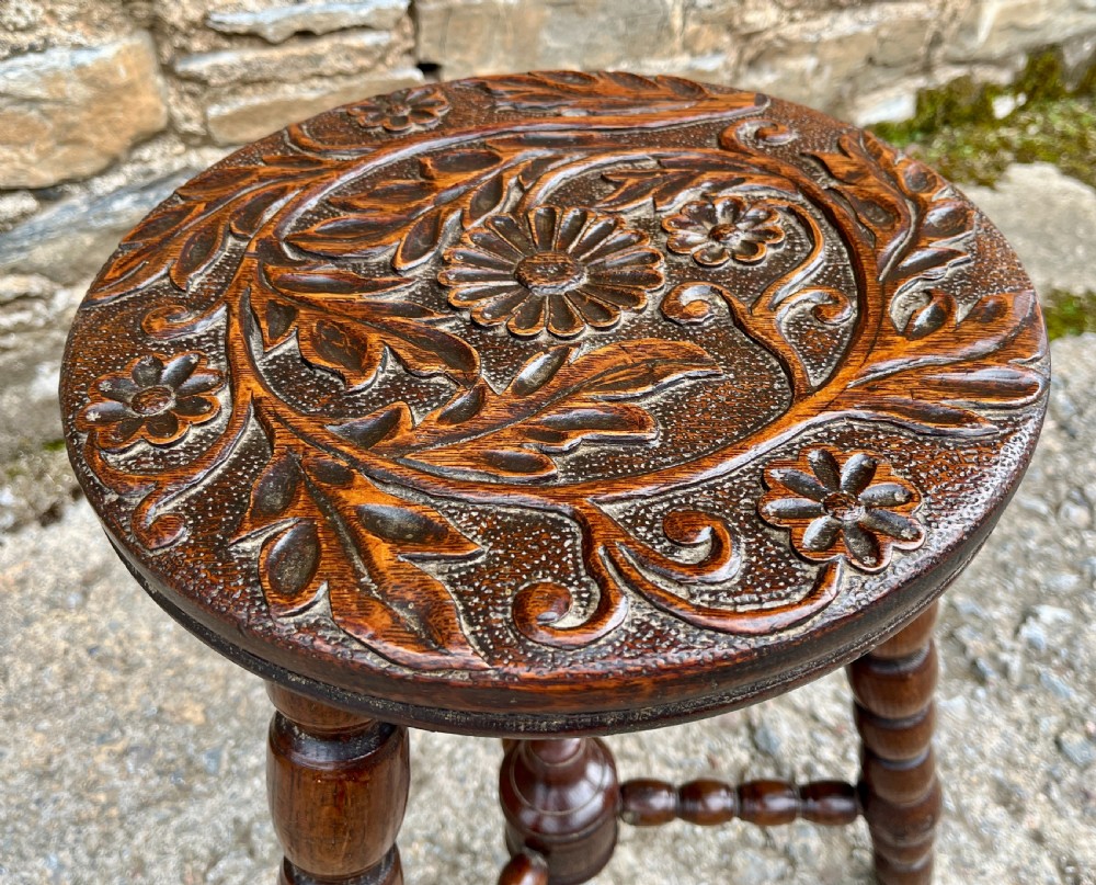 A small dark oak tripod table featuring bobbin-turned legs, a central turned stretcher, and a circular top hand-carved with floral patterns. View III
