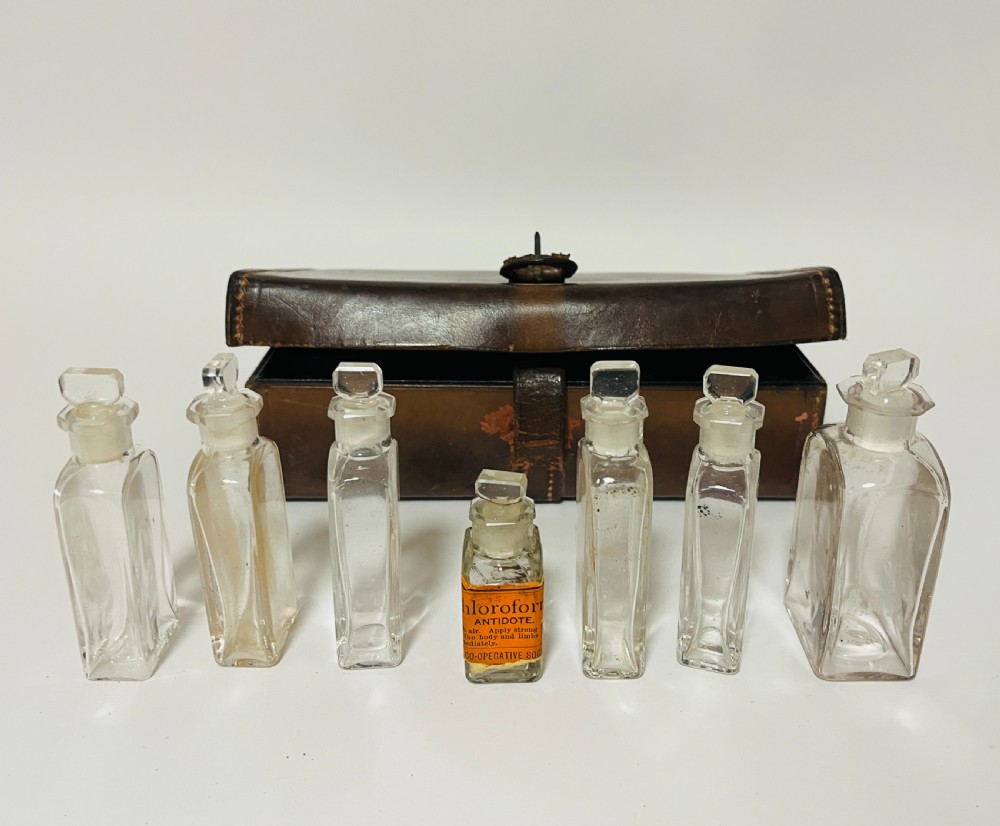 An open Victorian brown leather apothecary case revealing fitted compartments containing glass medicine bottles with stoppers and small metal tins. View V