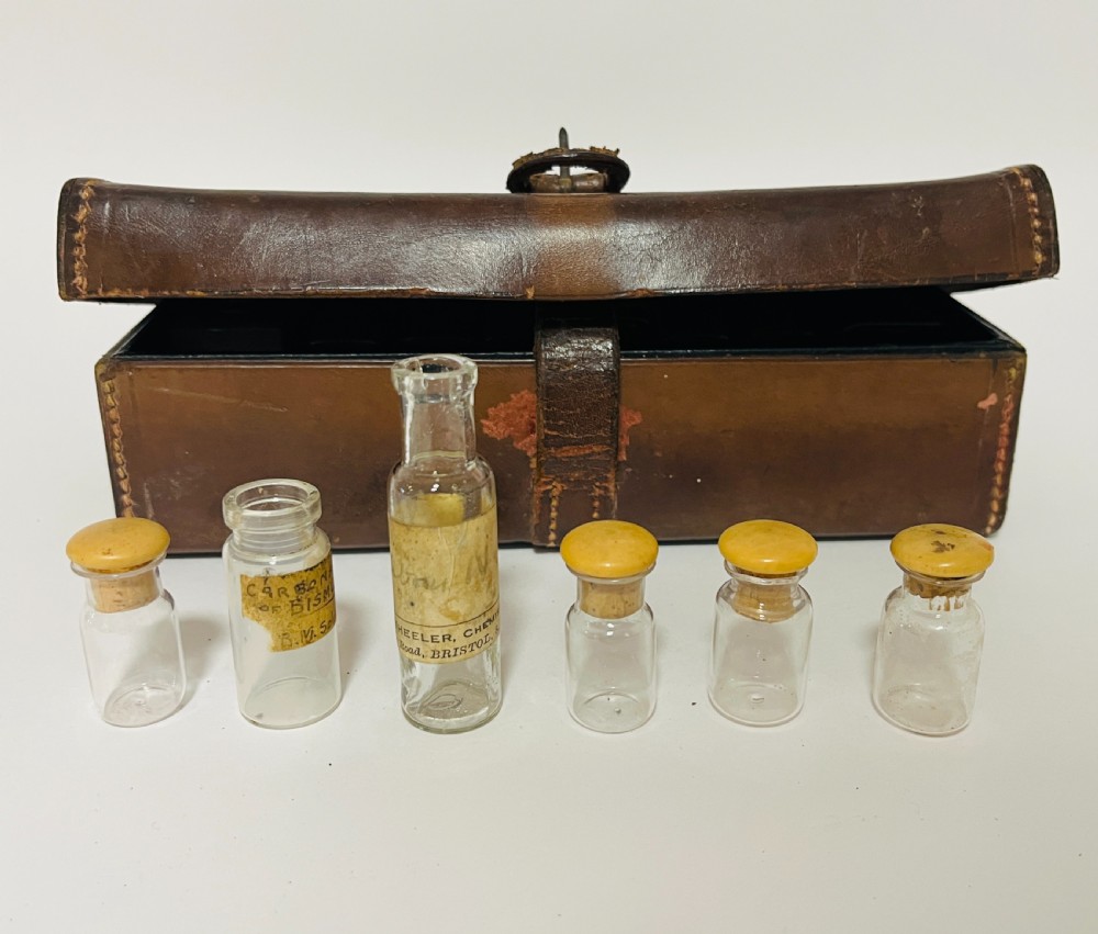 An open Victorian brown leather apothecary case revealing fitted compartments containing glass medicine bottles with stoppers and small metal tins. View VI