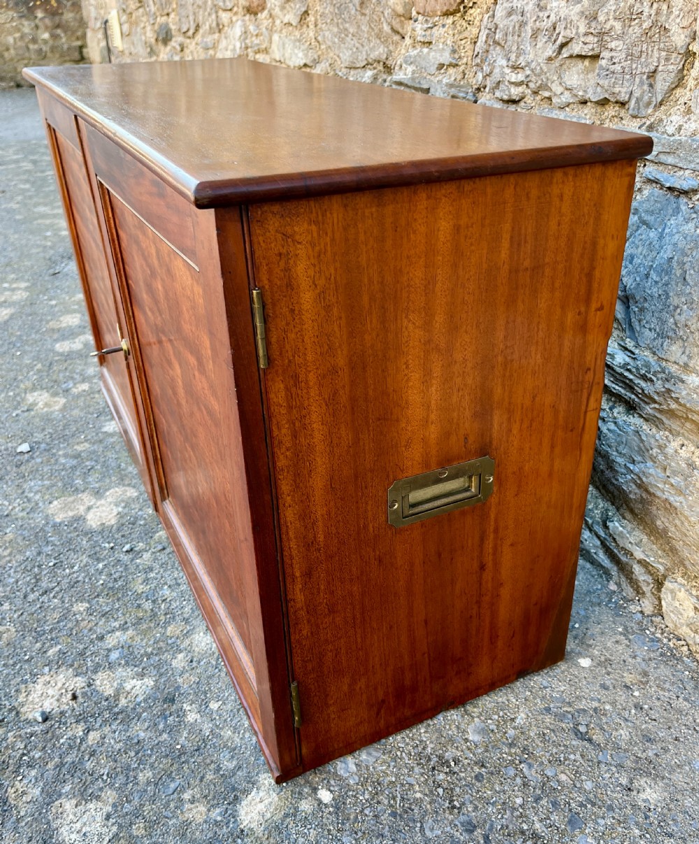 A low Victorian mahogany filing cabinet featuring twin panelled doors with flame mahogany veneer and a central keyhole. View VII