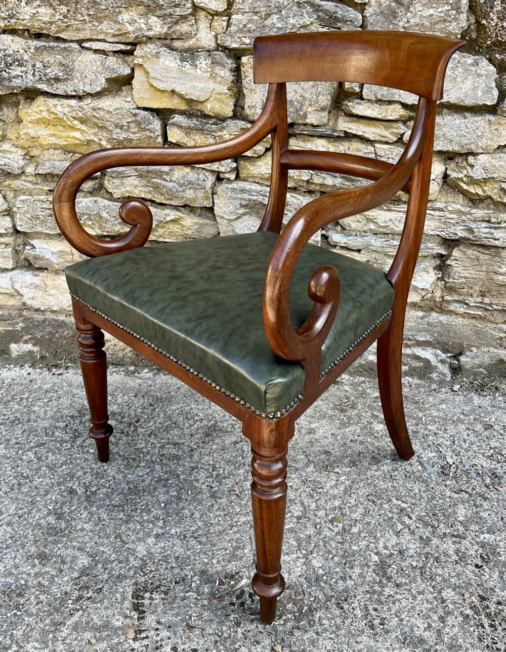 Victorian mahogany carver chair featuring dramatically scrolled armrests, a curved top rail, turned front legs, and a dark green leather seat trimmed with brass studs. View III