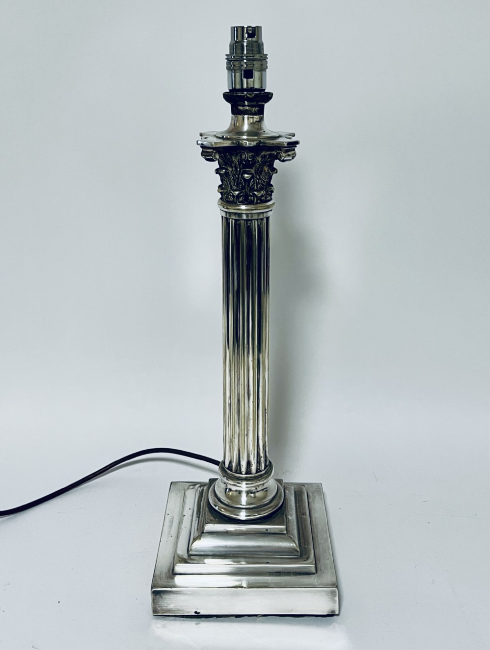 A Victorian silver-plated table lamp designed as a fluted Corinthian column with a stepped square base.