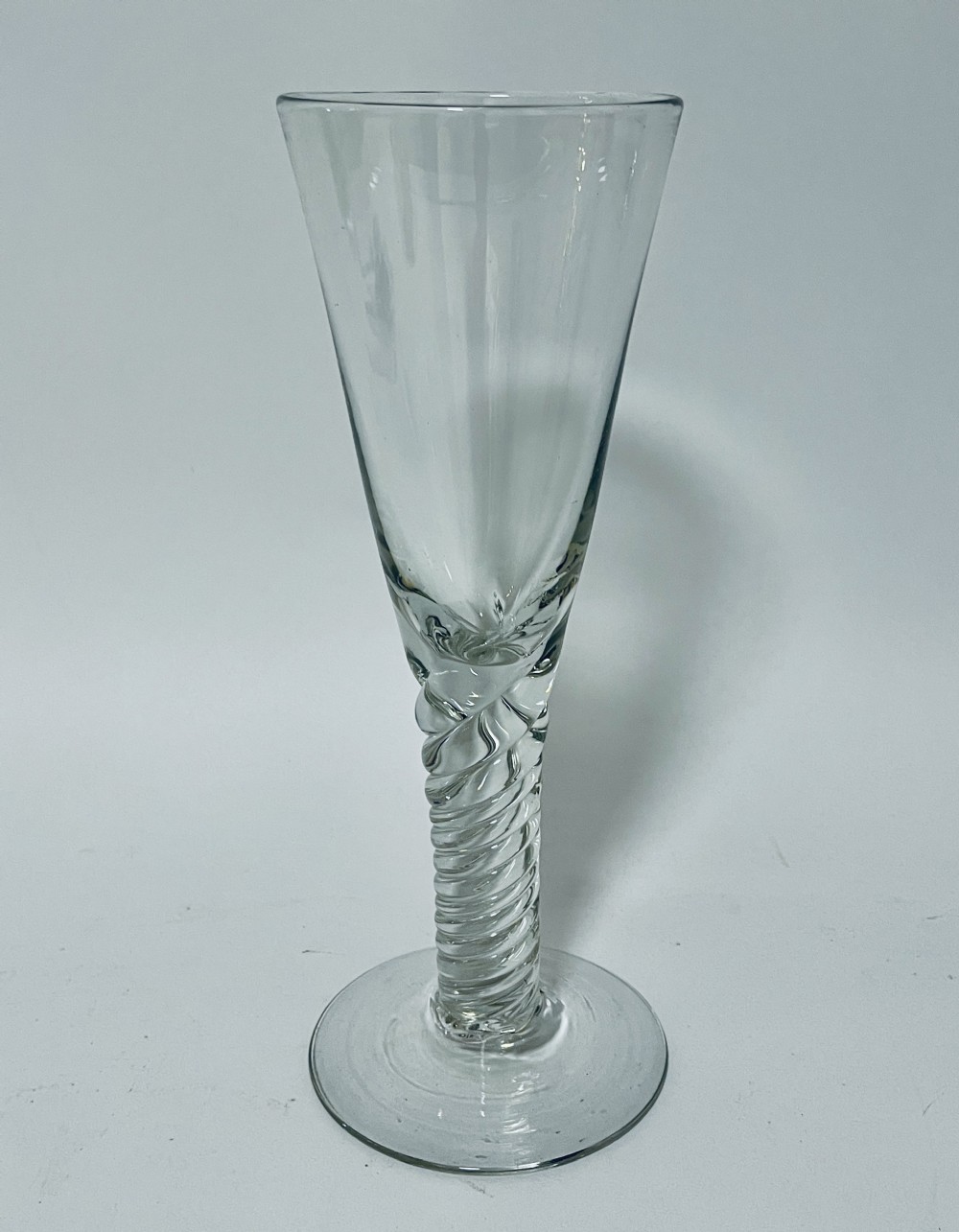 A tall clear hand-blown glass featuring a conical funnel-shaped bowl, a twisted wrythen stem, and a flat circular foot.