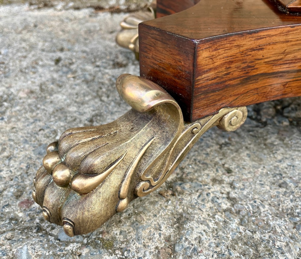 An antique Regency rosewood card table featuring a rectangular fold-over top, central tapered pedestal support, and a quadform base with brass claw feet. View V