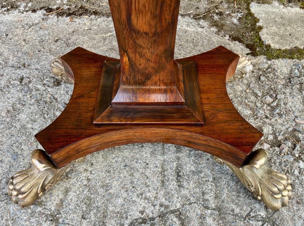 An antique Regency rosewood card table featuring a rectangular fold-over top, central tapered pedestal support, and a quadform base with brass claw feet. View VI