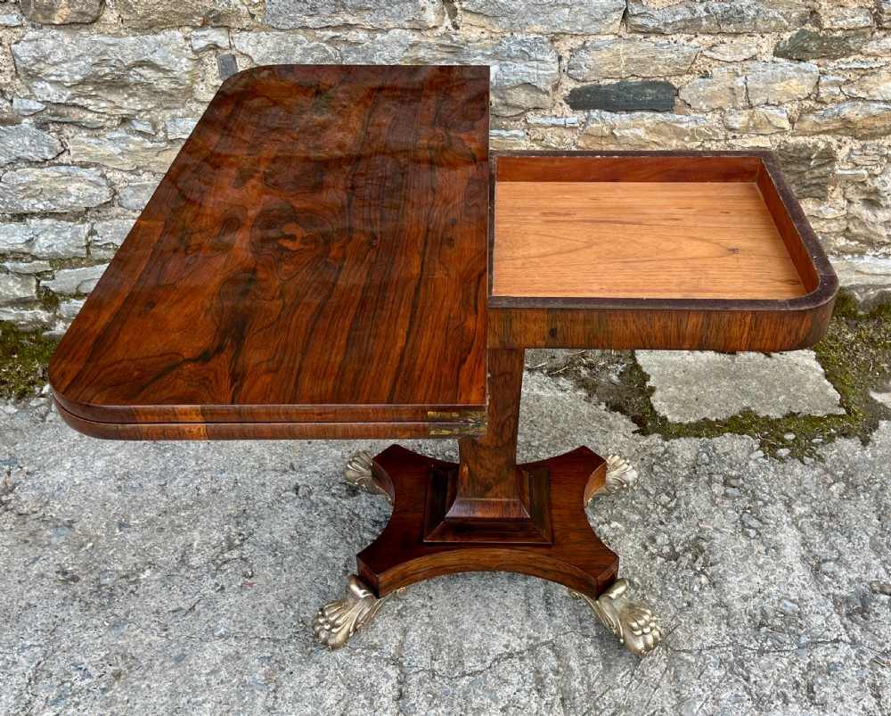 An antique Regency rosewood card table featuring a rectangular fold-over top, central tapered pedestal support, and a quadform base with brass claw feet. View VIII