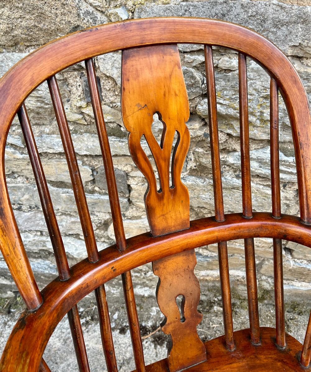 A warm brown wooden Windsor armchair featuring a curved hoop back, central pierced splat, turned spindles, shaped armrests, turned legs, and a crinoline stretcher. View VIII