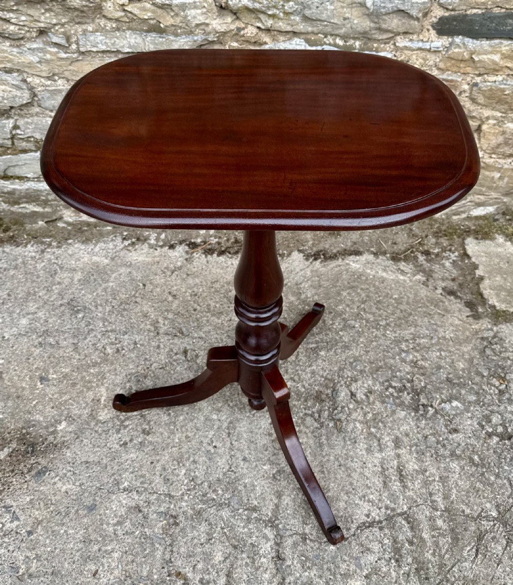 A Victorian dark mahogany wine table featuring a rounded rectangular top, a central turned baluster column, and a tripod base.