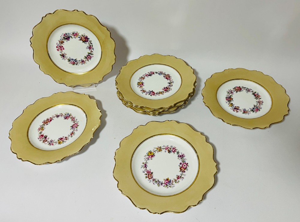 A nineteenth-century John Ridgway porcelain dessert service featuring buff-coloured borders, gilded scrollwork, reticulated handles, and hand-painted central floral garlands. View IV