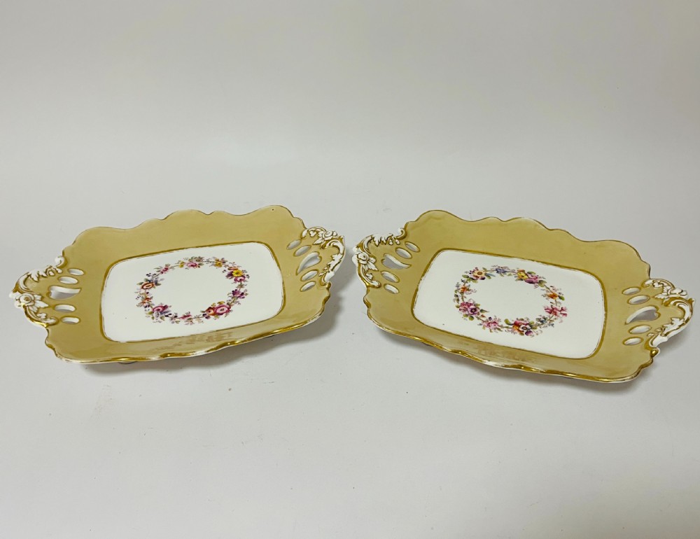 A nineteenth-century John Ridgway porcelain dessert service featuring buff-coloured borders, gilded scrollwork, reticulated handles, and hand-painted central floral garlands. View IX