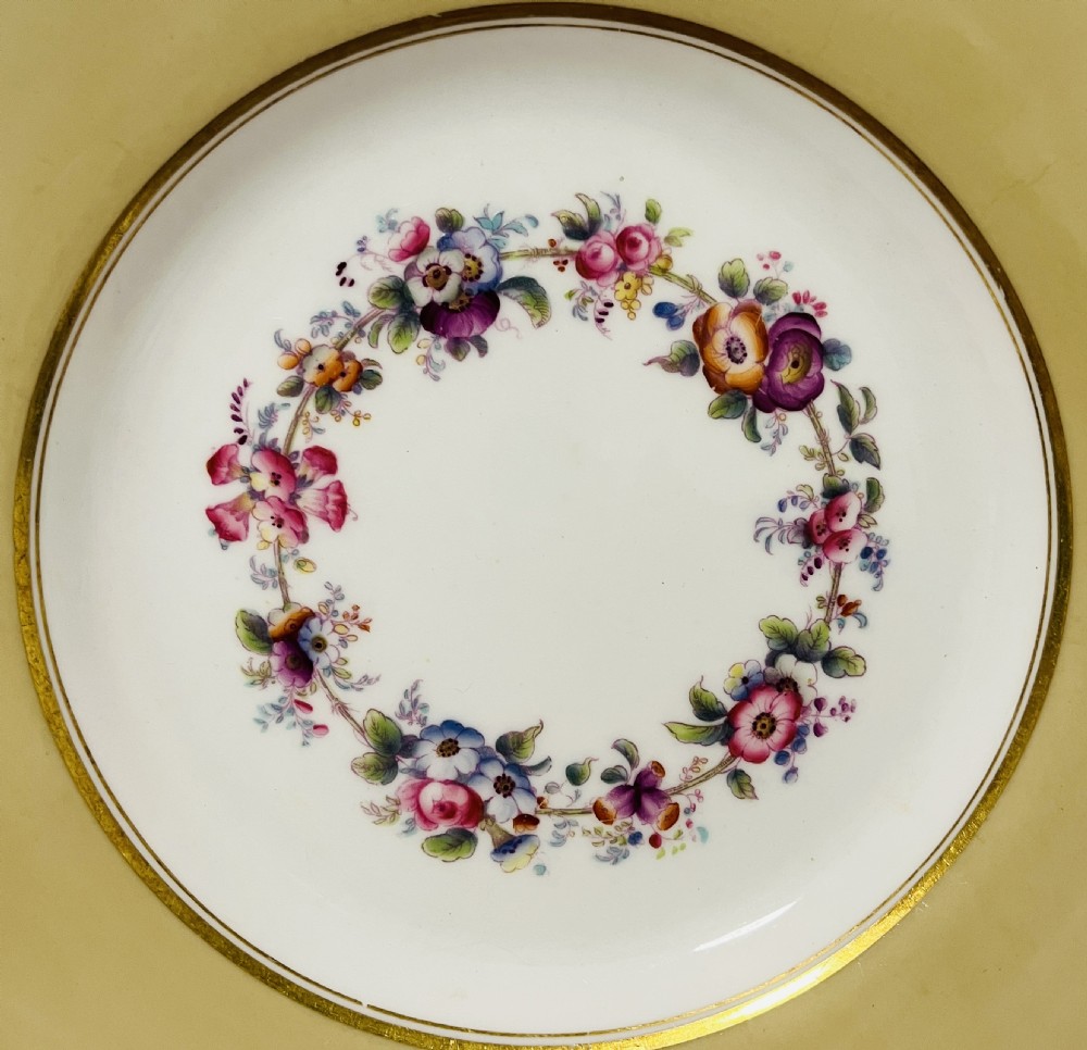 A nineteenth-century John Ridgway porcelain dessert service featuring buff-coloured borders, gilded scrollwork, reticulated handles, and hand-painted central floral garlands. View X