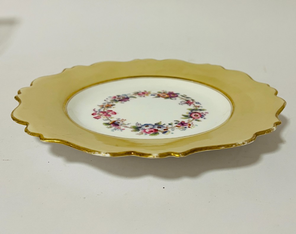 A nineteenth-century John Ridgway porcelain dessert service featuring buff-coloured borders, gilded scrollwork, reticulated handles, and hand-painted central floral garlands. View XIV
