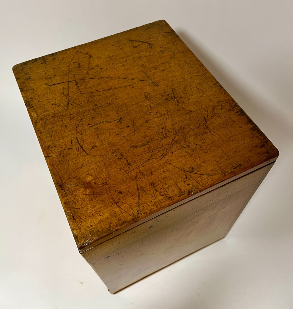 A warm brown wooden microscope slide cabinet with its single door open to reveal numerous shallow horizontal drawers with small round pulls. View VII