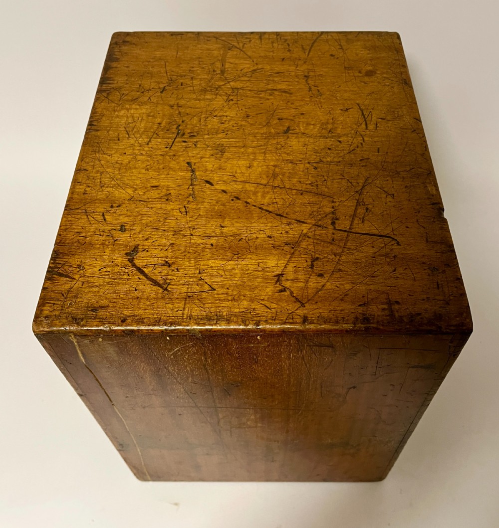 A warm brown wooden microscope slide cabinet with its single door open to reveal numerous shallow horizontal drawers with small round pulls. View VIII