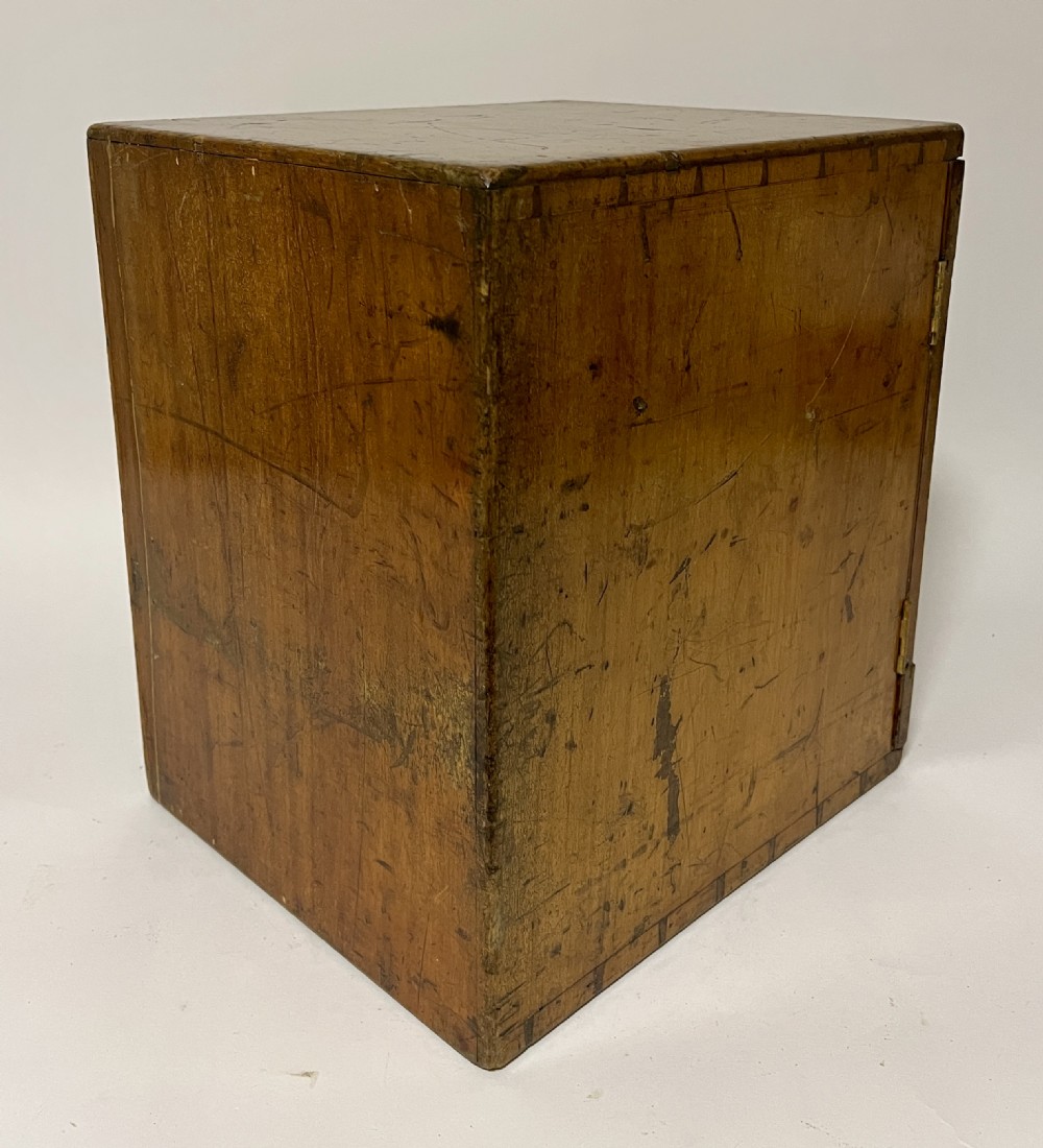 A warm brown wooden microscope slide cabinet with its single door open to reveal numerous shallow horizontal drawers with small round pulls. View XI