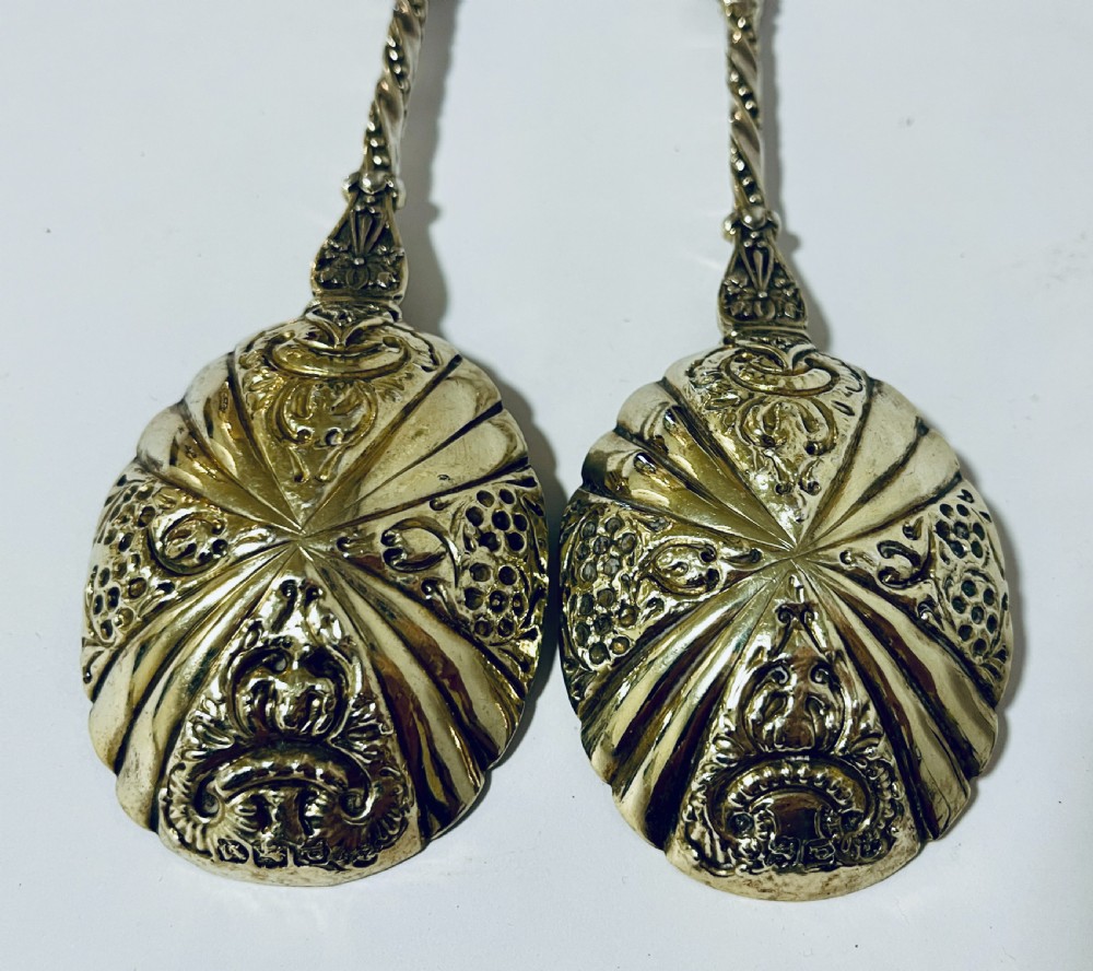 A pair of Victorian silver-gilt serving spoons featuring fluted embossed bowls with scroll patterns and twisted handles. View III