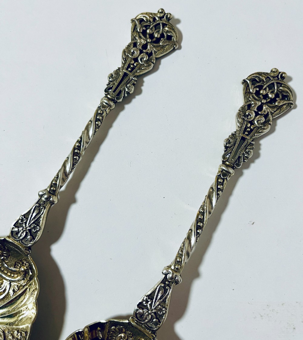 A pair of Victorian silver-gilt serving spoons featuring fluted embossed bowls with scroll patterns and twisted handles. View IV