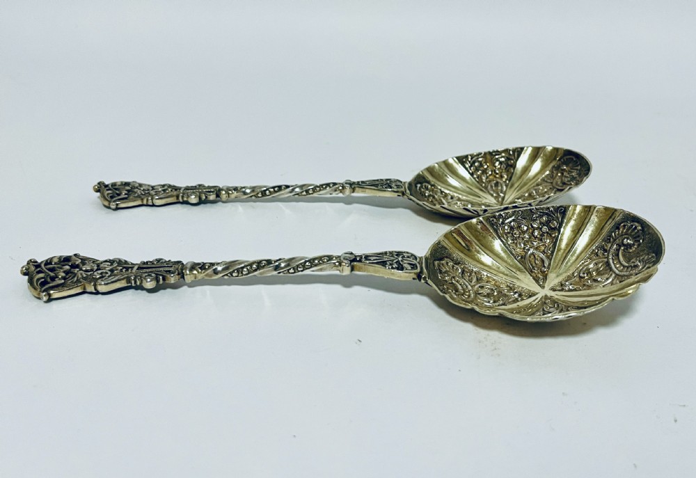 A pair of Victorian silver-gilt serving spoons featuring fluted embossed bowls with scroll patterns and twisted handles. View V