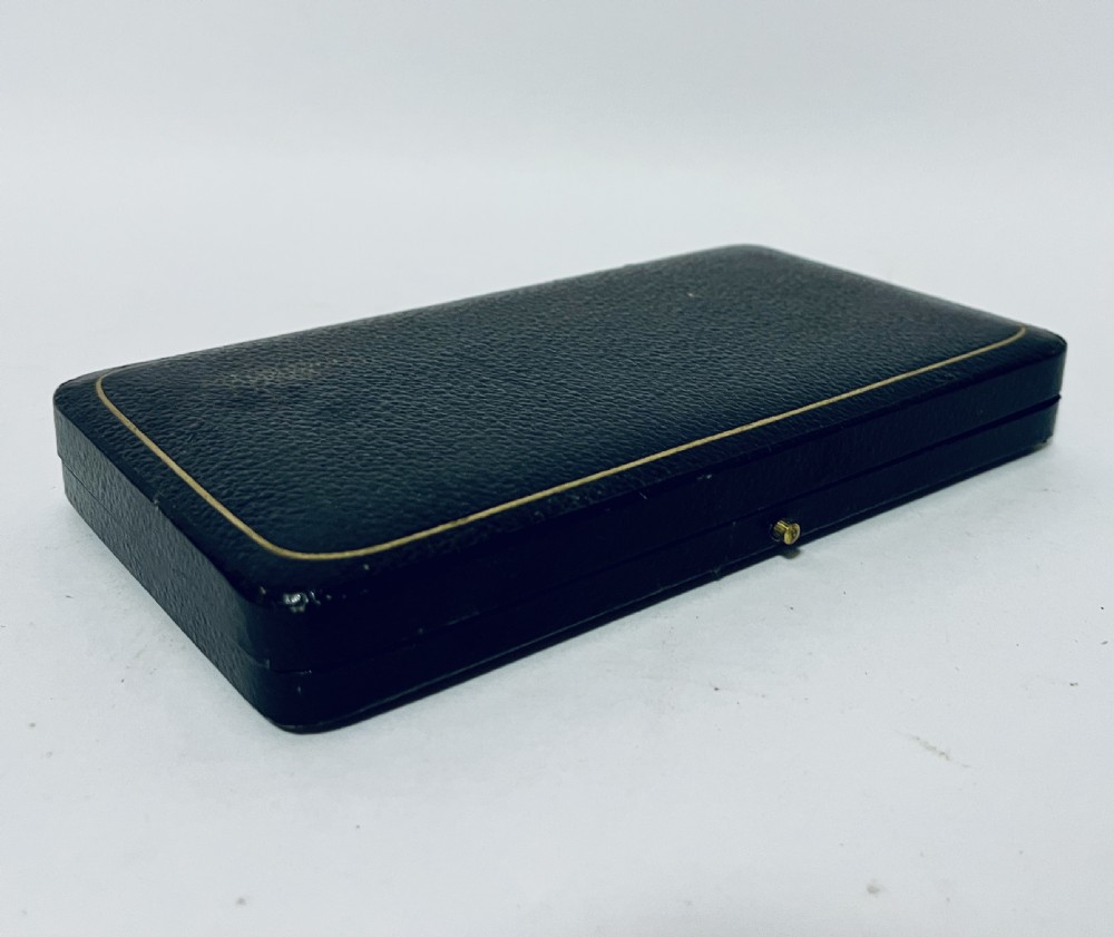 An antique silver christening spoon and fork set presented inside an open black fitted case lined with cream silk and dark velvet. View V