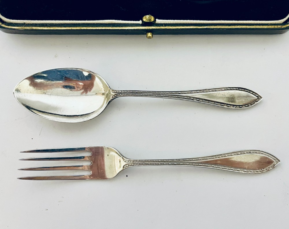 An antique silver christening spoon and fork set presented inside an open black fitted case lined with cream silk and dark velvet. View VI