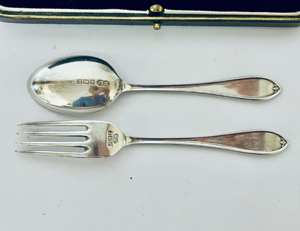 An antique silver christening spoon and fork set presented inside an open black fitted case lined with cream silk and dark velvet. View VIII