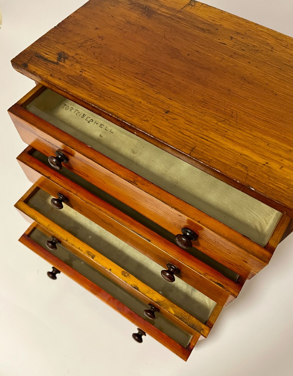 An antique stained pine specimen cabinet featuring four horizontal drawers with turned dark wood knobs and a solid plinth base. View III