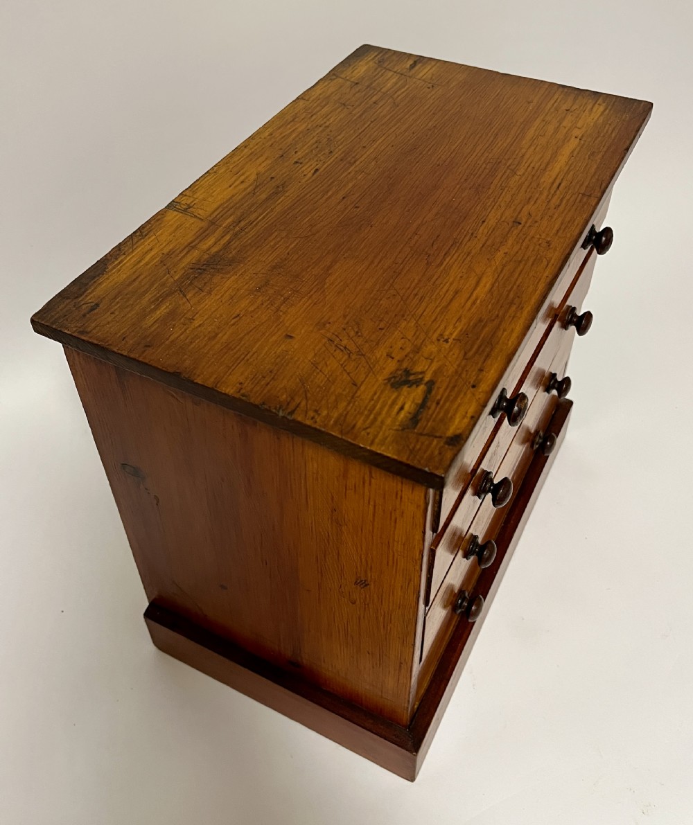 An antique stained pine specimen cabinet featuring four horizontal drawers with turned dark wood knobs and a solid plinth base. View XIV
