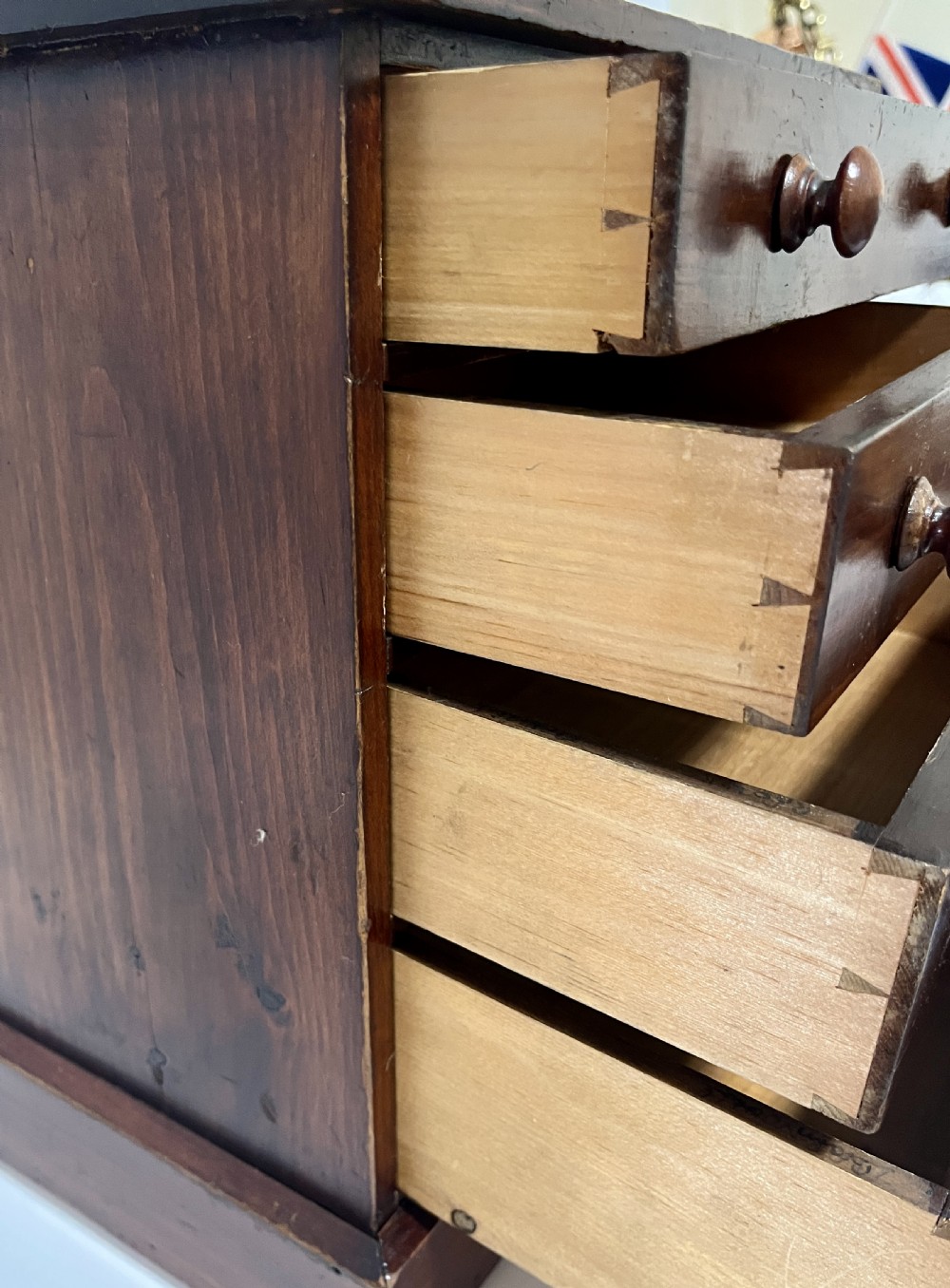 A small antique stained pine tabletop collectors cabinet featuring four drawers with turned wooden knobs on a plinth base. View IX