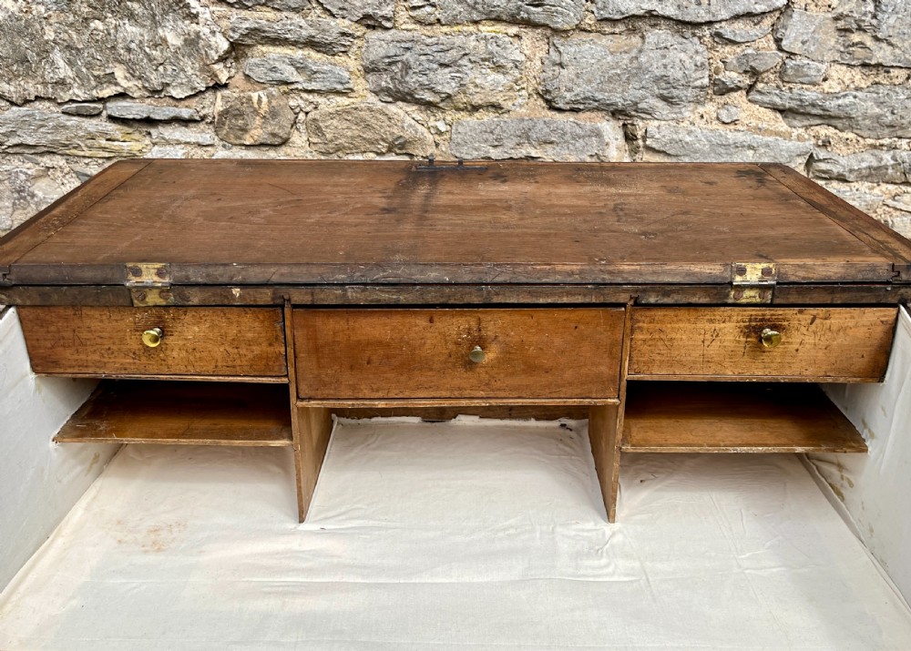 A Georgian solid oak clerks desk featuring a hinged sloped writing top, a key with tassel inserted into the central keyhole, and four square tapered legs. View XII