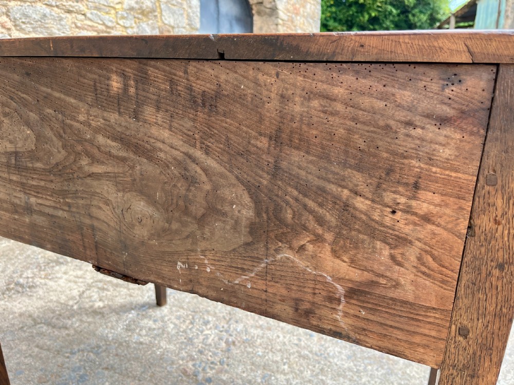 A Georgian solid oak clerks desk featuring a hinged sloped writing top, a key with tassel inserted into the central keyhole, and four square tapered legs. View XX